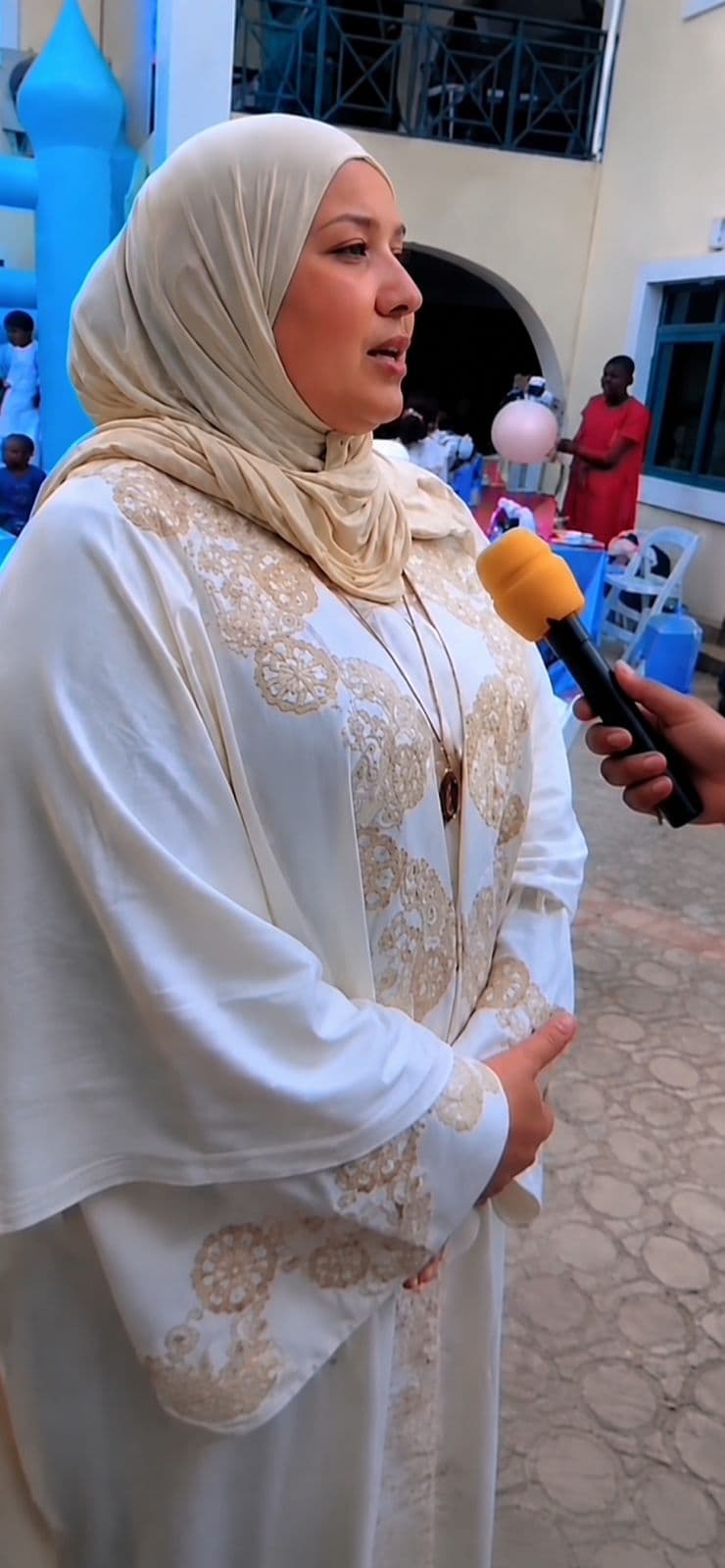 Ahlam Musa speaking into a microphone, outdoors.